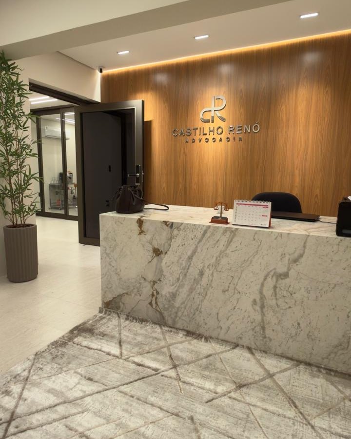 Recepção do escritório, com painel de madeira e o letreiro do Castilho Renó Advocacia